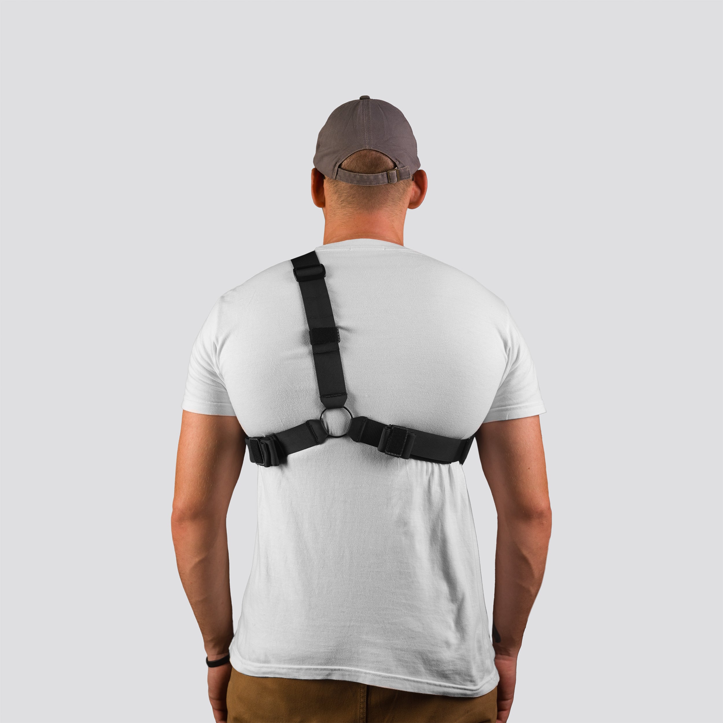 Man wearing a black shoulder brace on a plain background