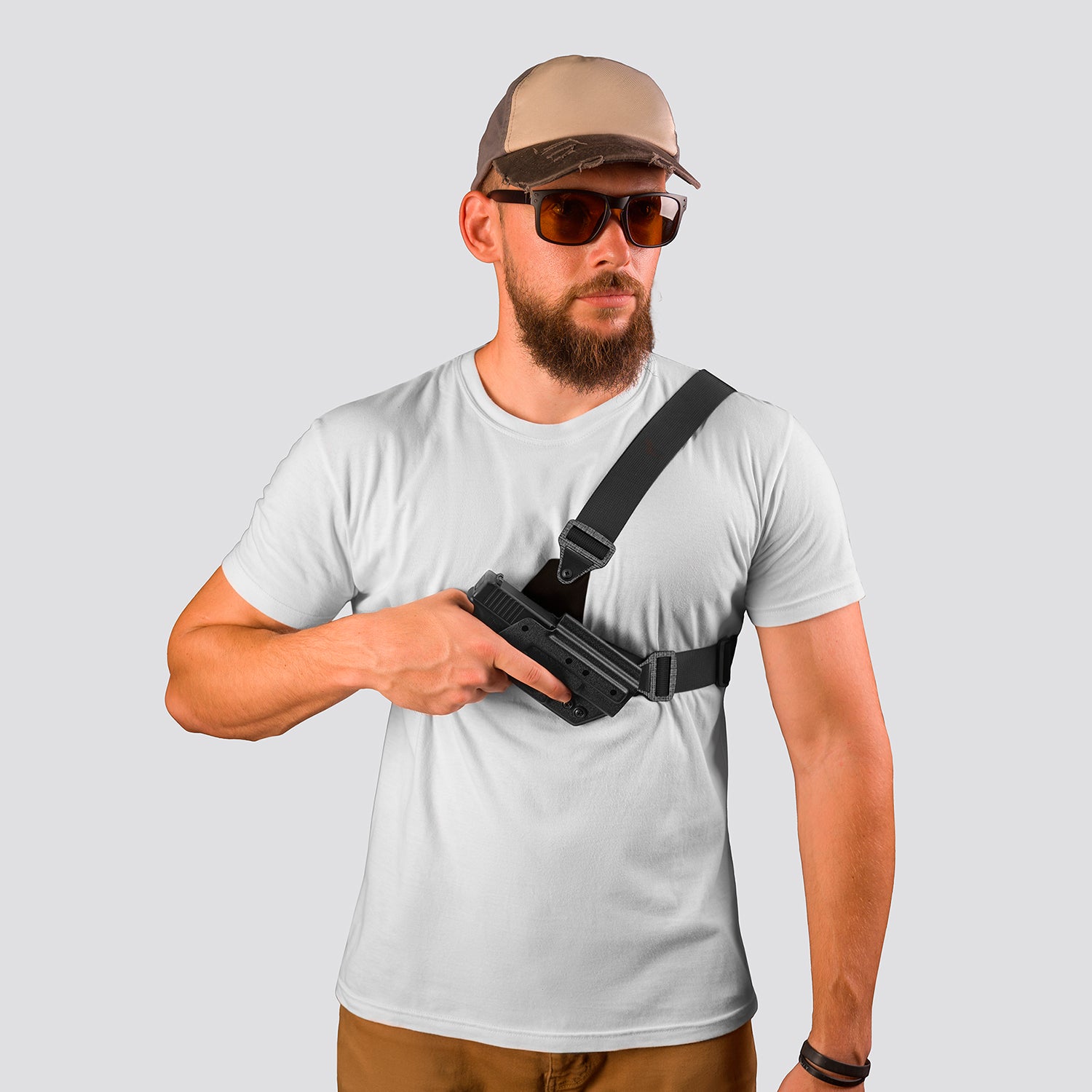 Man wearing a white t-shirt, brown cap, sunglasses, and holding a black gun holster on a light gray background